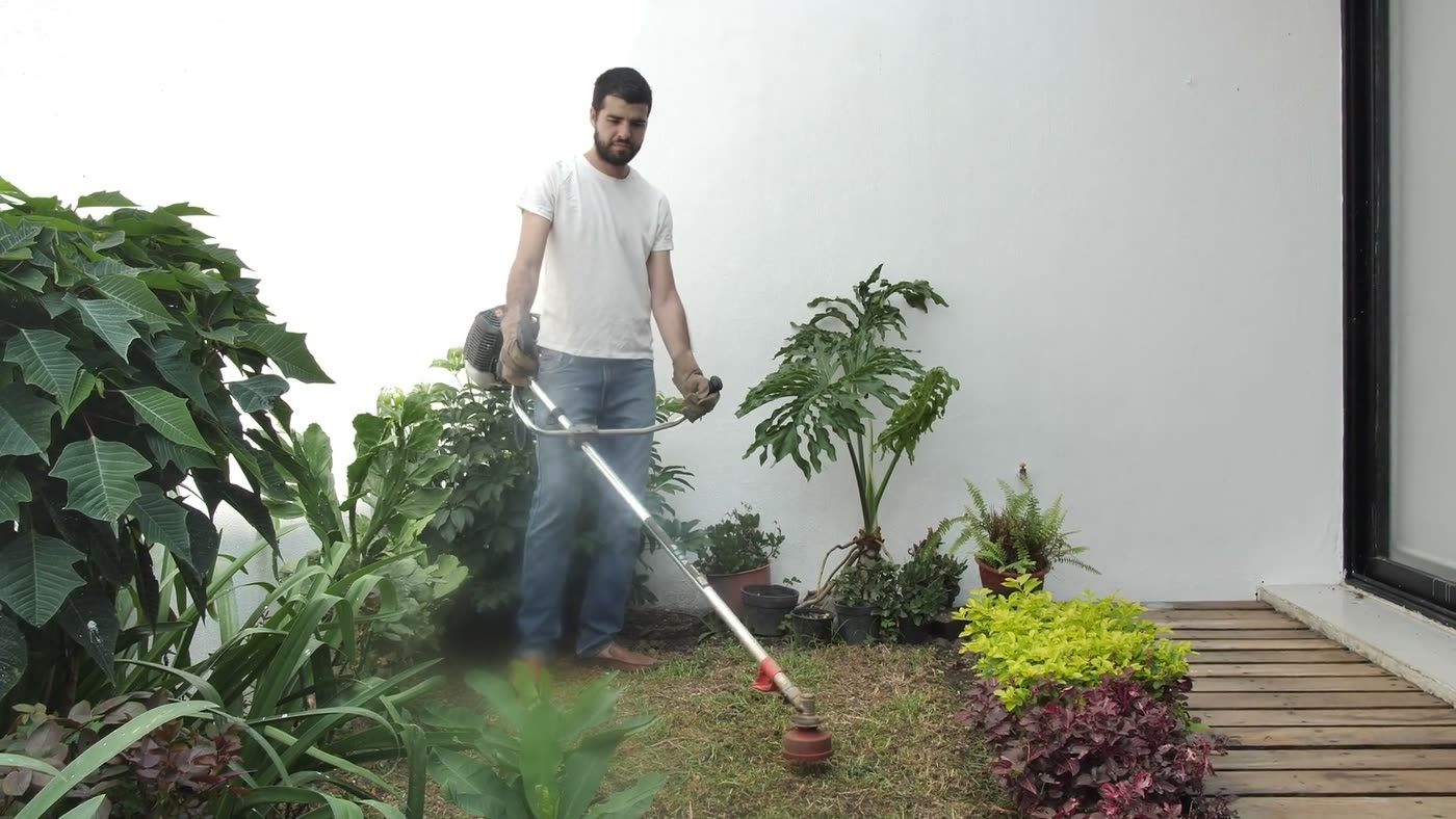 A crew member trimming the grass edge along a garden bed
